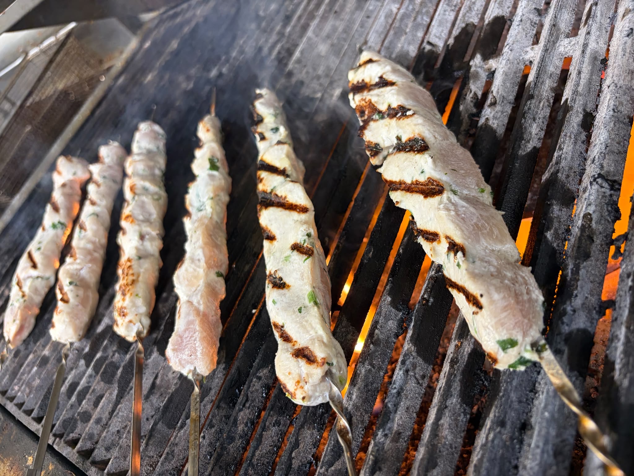 Marinated chicken skewers cooking over charcoal
