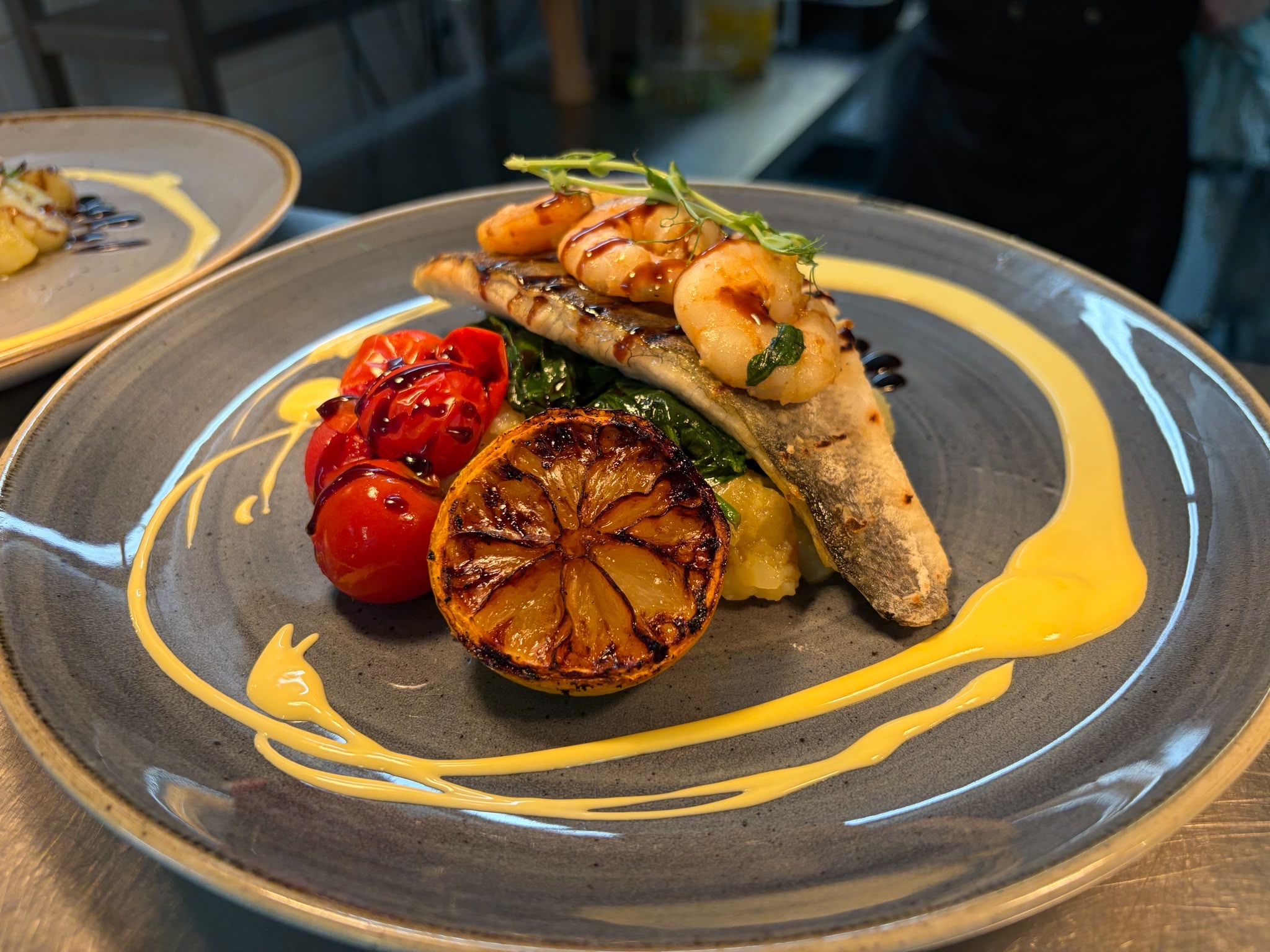 Sea bass with prawns, greens, tomatoes and charred lemon