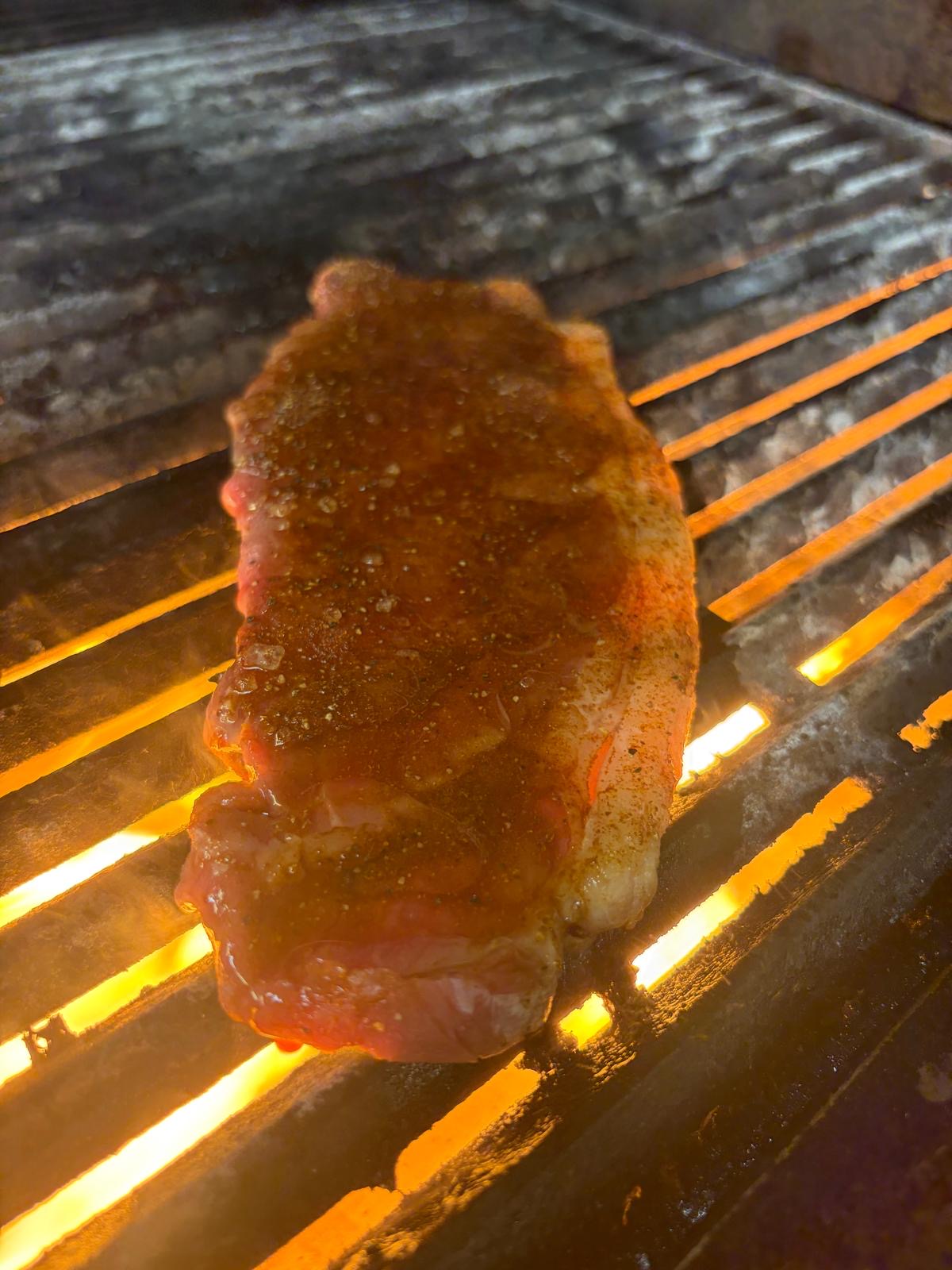 Seasoned steak placed over the fire